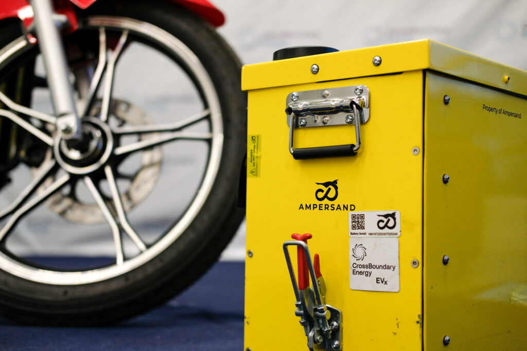 An electric battery in front of an e-motor, showing the CrossBoundary Energy and Ampersand logos
